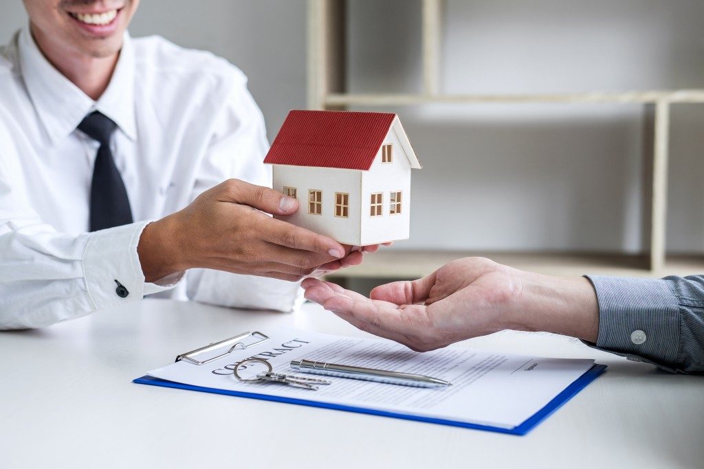 Real estate agent handing house model to client