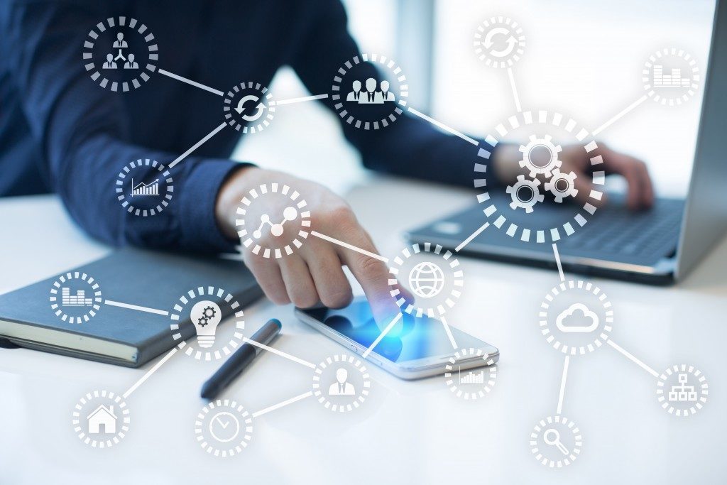 Man working with laptop and phone with business and tech icons overlayed