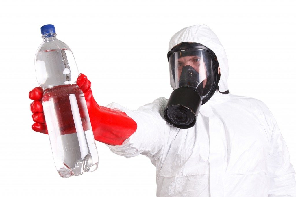 Man in protective suit with a bottle of pure water isolated on white