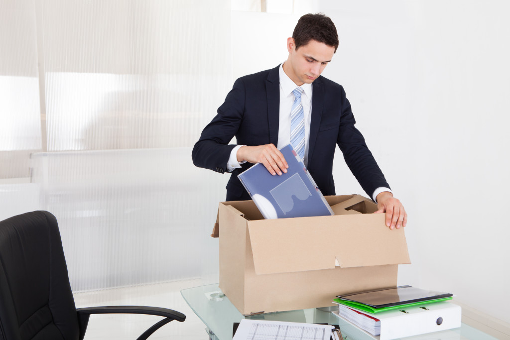 packing files in cardboard box at desk in office