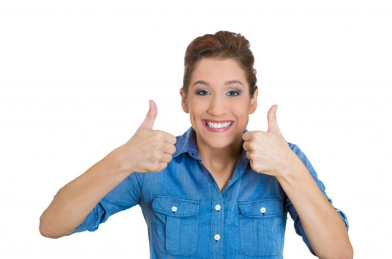 A woman in a blue polo shirt raising her two thumbs up while smiling to the camera