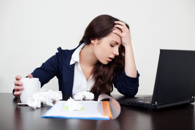 A woman with crumpled tissues and headache in the office