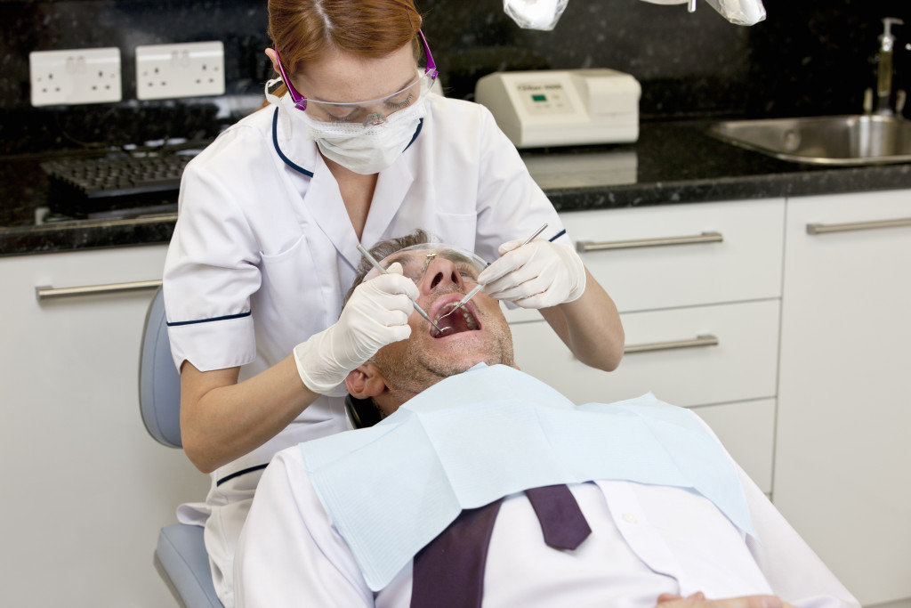 A dentist examines a patient's teeth for possible damage