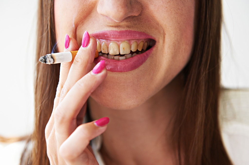 A woman with yellow teeth, smoking a cigarette