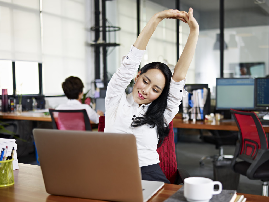 Female employee stretching while seated in the office.