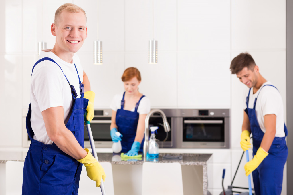 a group of people cleaning the kitchen area of house